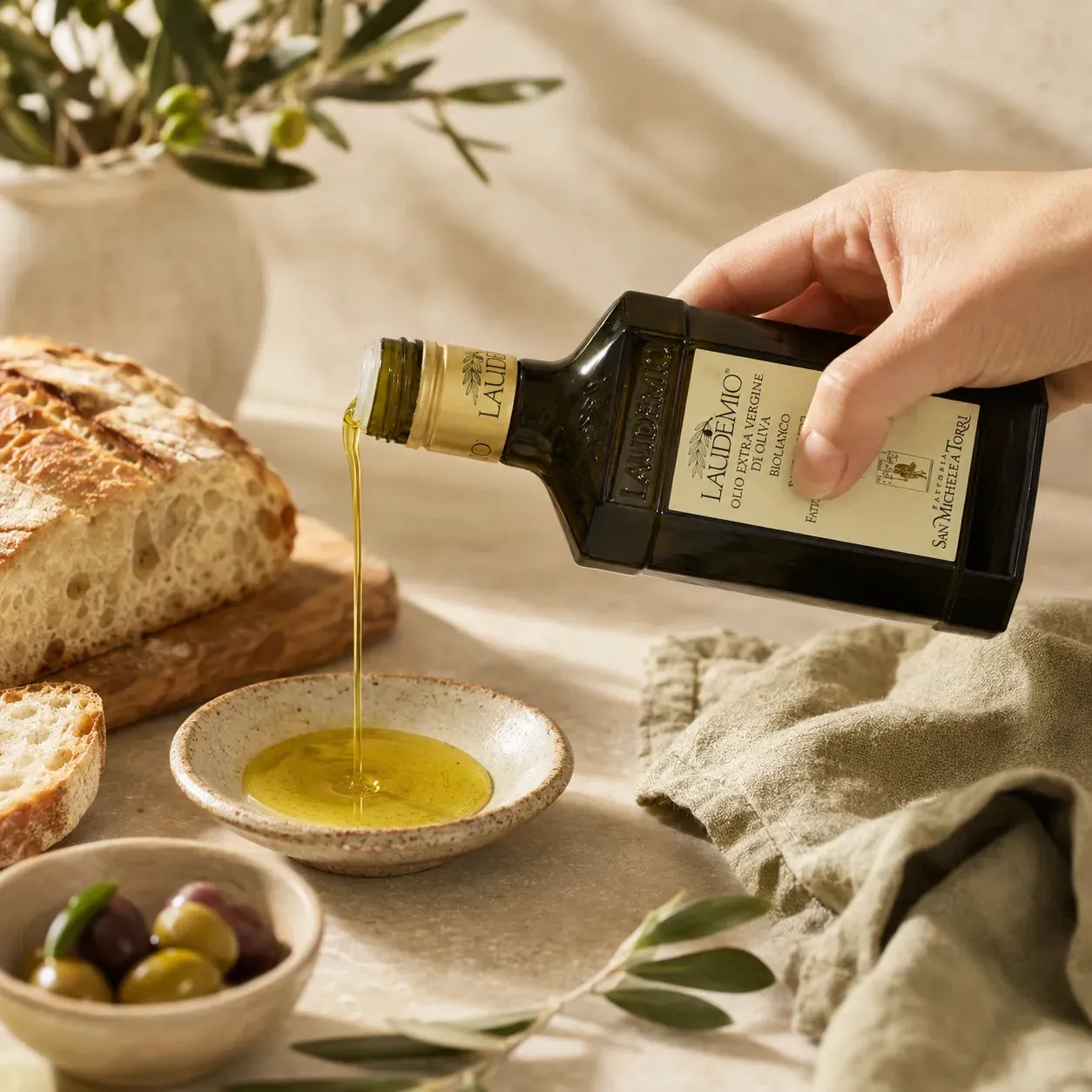 Laudemio poured into a bowl beside fresh bread